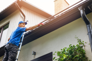 Man on ladder while cleaning gutters.