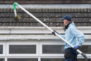 Man using tool to suction grime from gutters.