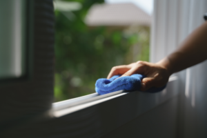 Person wipping out the window sill.