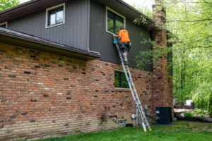 Professional window cleaner standing on tall latter as he cleans high window.