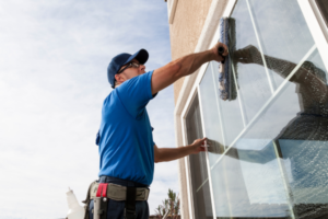 Man wearing cap as he cleans windows  in the exterior.